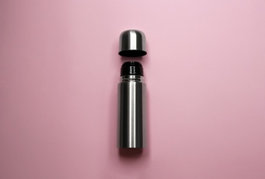 Stainless steel thermos on pink background, top view