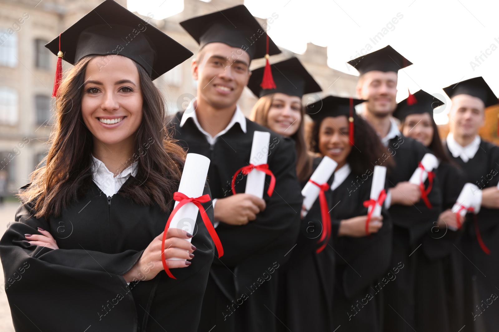 Photo of Happy students with diplomas outdoors. Graduation ceremony