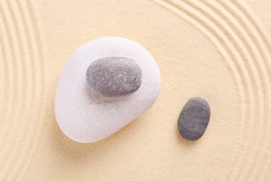 Photo of Zen garden stones on sand with pattern, flat lay