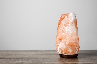 Himalayan salt lamp on table against light background