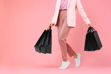 Photo of Woman with shopping bags on pink background, closeup