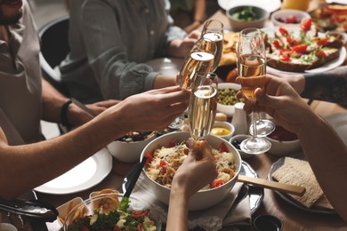 Photo of Group of people clinking glasses with champagne during brunch at table, closeup
