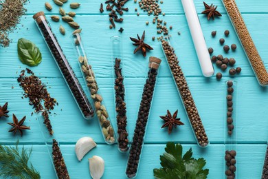 Photo of Flat lay composition with various spices, test tubes and fresh herbs on light blue wooden background
