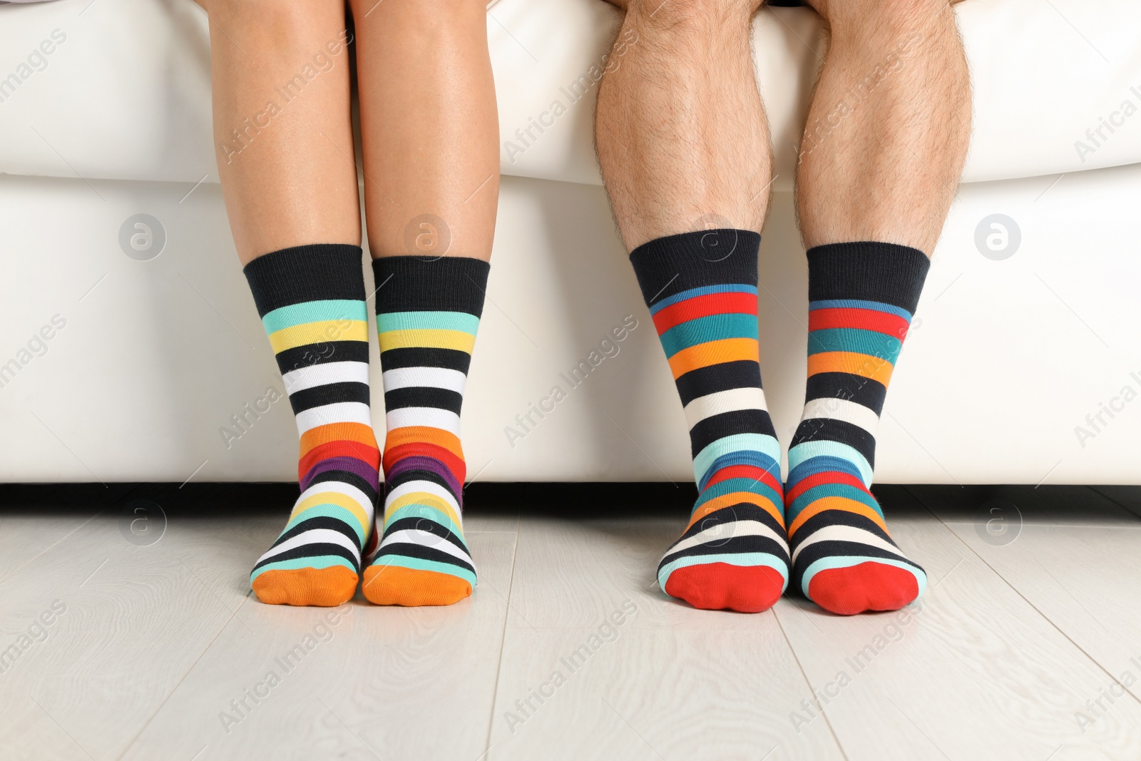 Photo of Young couple in matching socks on couch indoors, closeup