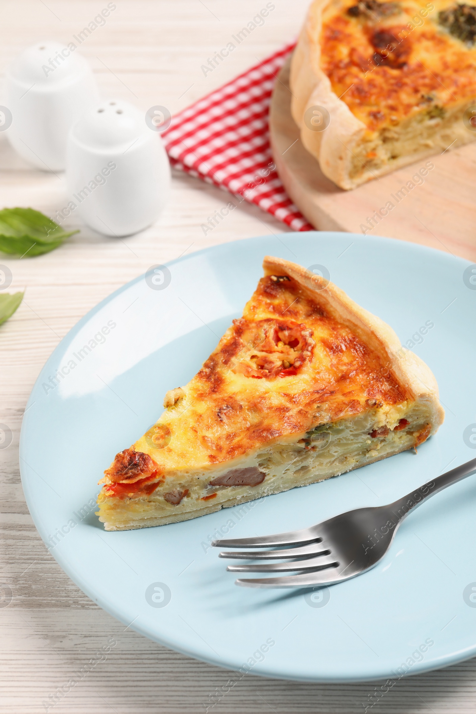 Photo of Delicious homemade vegetable quiche and fork on white wooden table