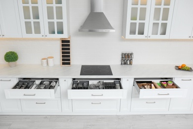 Open drawers with different utensils in kitchen