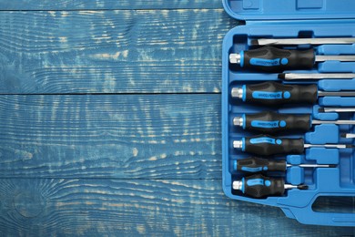 Photo of Set of screwdrivers in open toolbox on blue wooden table, top view. Space for text
