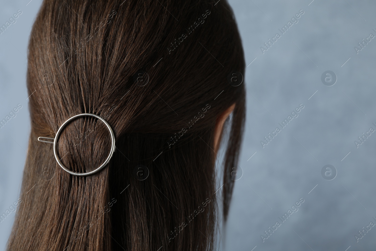 Photo of Young woman with beautiful hair clip on blue background, closeup