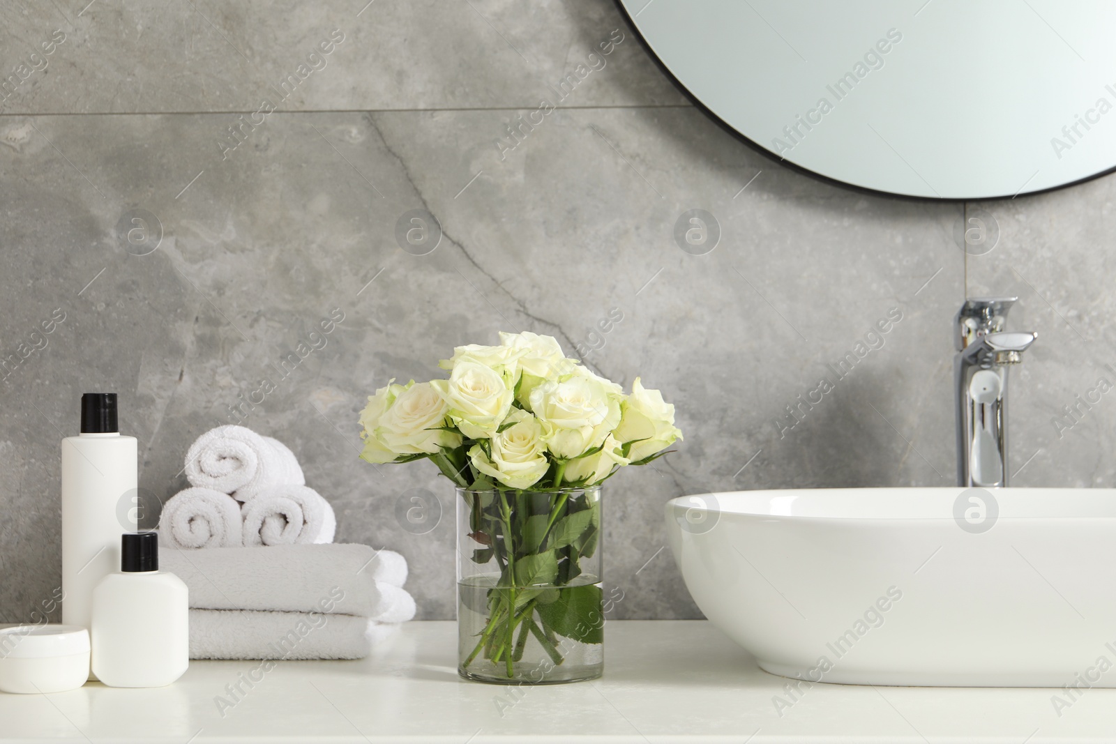 Photo of Beautiful roses and bath accessories near sink in bathroom