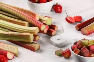 Whole and cut rhubarb stalks on white wooden table, closeup