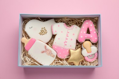 Set of baby shower cookies in gift box on light pink background, top view