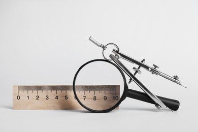 Photo of Ruler, magnifying glass and compass on white background