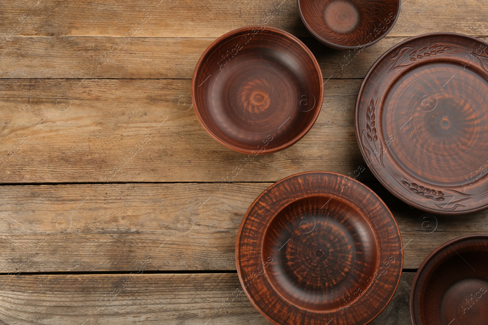 Photo of Set of clay utensils on wooden table, flat lay. Space for text