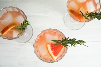 Glasses of grapefruit cocktails on white table, flat lay