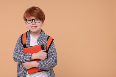 Photo of Happy schoolboy with book on beige background. Space for text