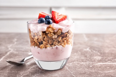 Glass with yogurt, berries and granola on table