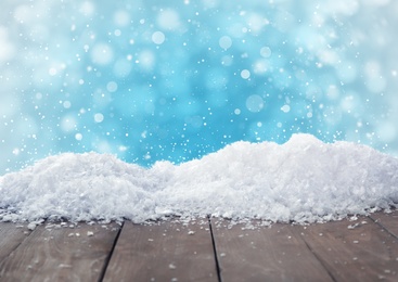 Image of Wooden surface with snow against light blue background, bokeh effect