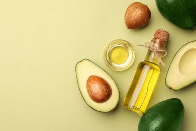 Photo of Cooking oil and fresh avocados on light green background, flat lay. Space for text