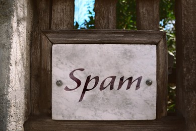 Metal sign with word Spam on wooden fence outdoors