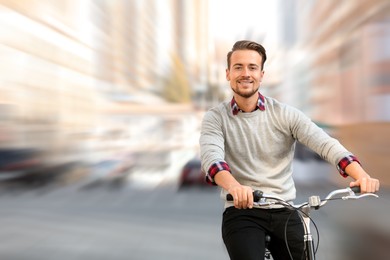 Image of Handsome happy man riding bicycle on city street, motion blur effect
