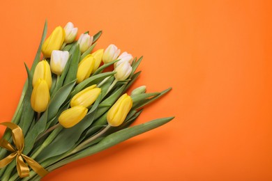 Bouquet of beautiful yellow tulips on orange background, top view. Space for text