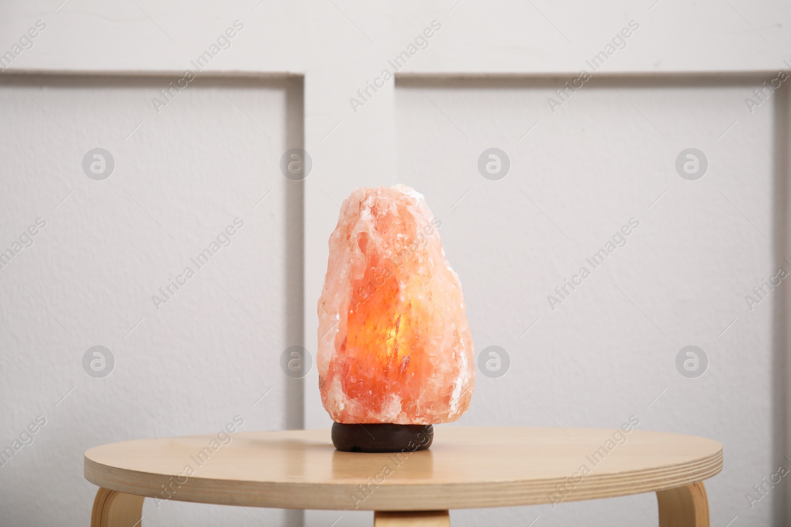 Photo of Himalayan salt lamp on wooden table indoors