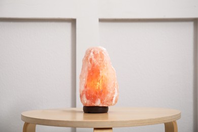 Photo of Himalayan salt lamp on wooden table indoors