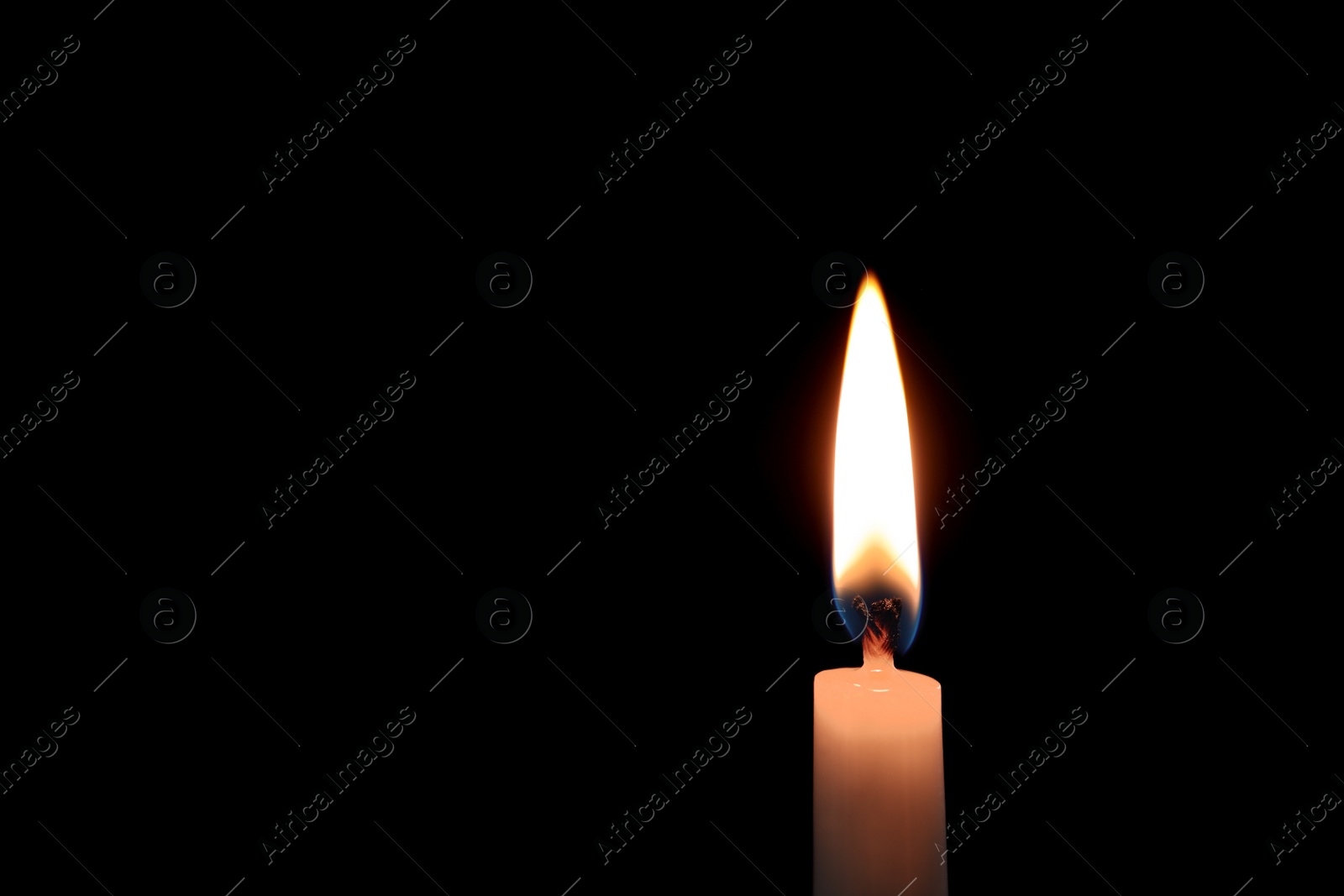 Photo of Wax candle burning on black background