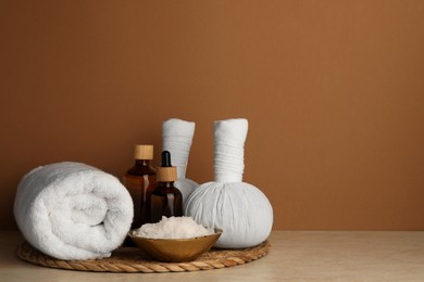 Photo of Composition with different spa products on beige table against brown background. Space for text