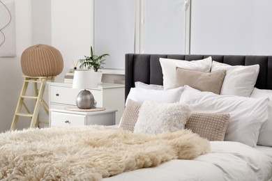Photo of Stylish soft light bedroom interior with large comfortable bed, chest of drawers and table lamp