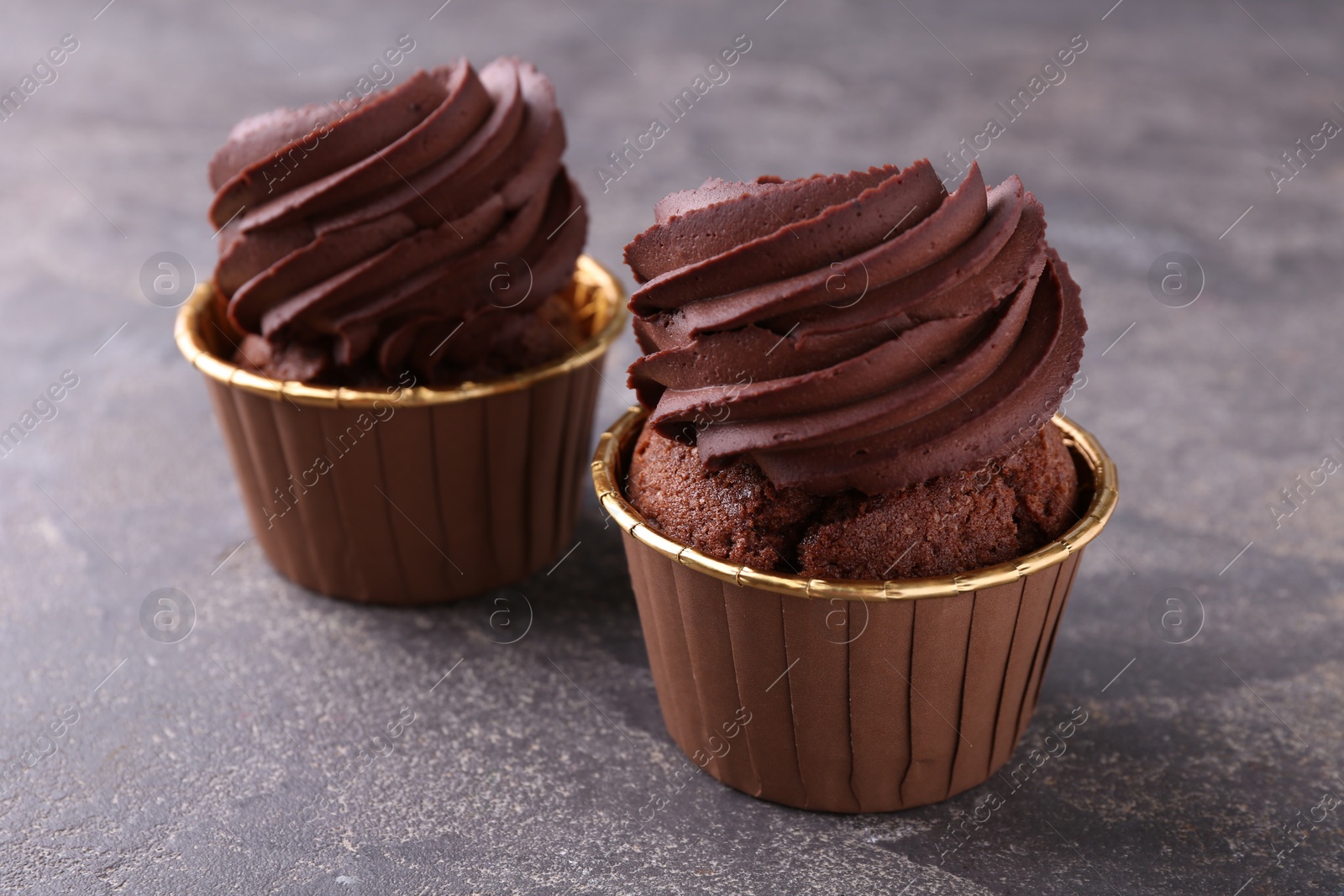 Photo of Delicious chocolate cupcakes on grey table, closeup