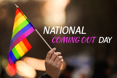 Image of National Coming Out day. Woman holding small LGBT flag on city street, closeup