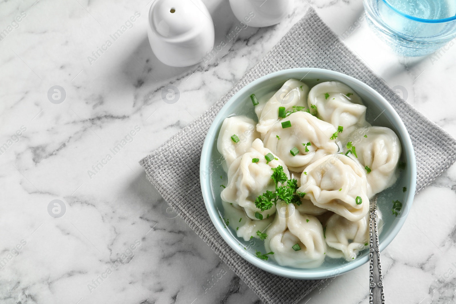 Photo of Bowl of tasty dumplings served on white marble table, top view. Space for text