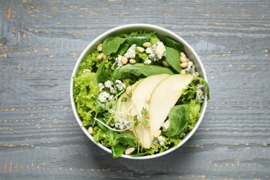 Fresh salad with pear on grey wooden table, top view