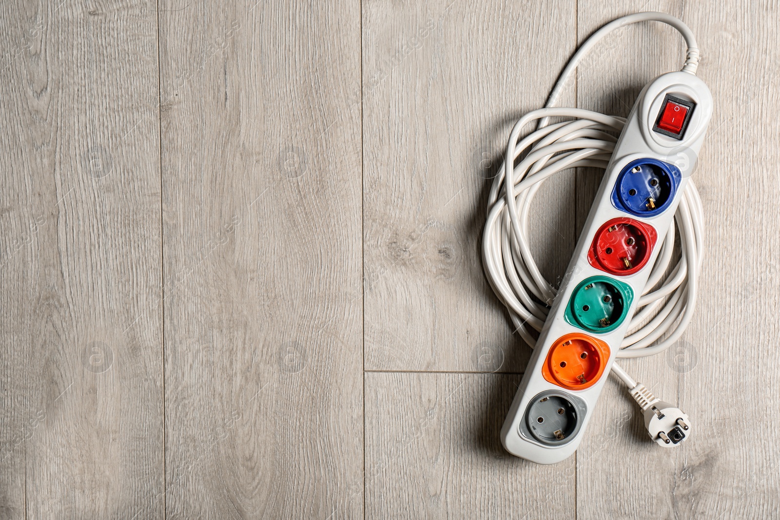 Photo of Extension cord on wooden floor, top view with space for text. Electrician's equipment