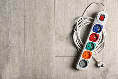 Photo of Extension cord on wooden floor, top view with space for text. Electrician's equipment