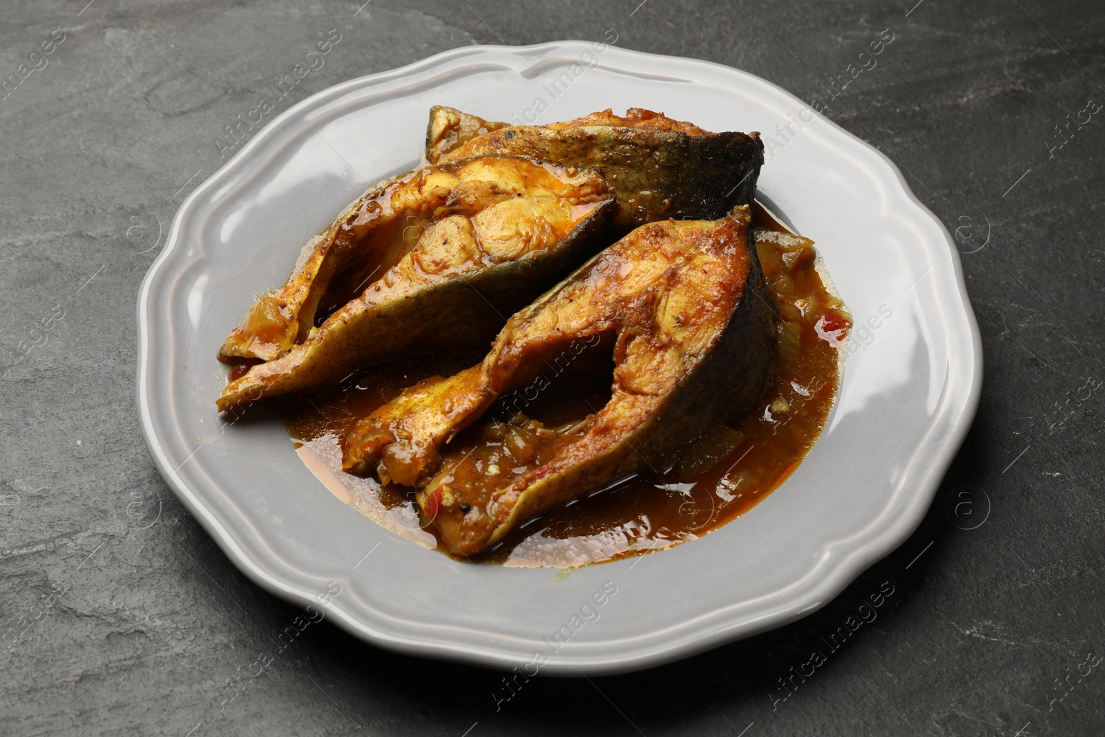 Photo of Tasty fish curry on grey textured table, closeup. Indian cuisine