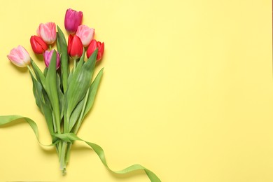 Photo of Beautiful colorful tulips on pale yellow background, flat lay. Space for text