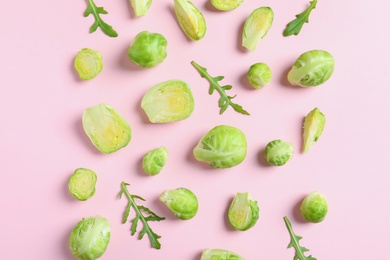 Photo of Fresh Brussels sprouts and arugula on color background, flat lay