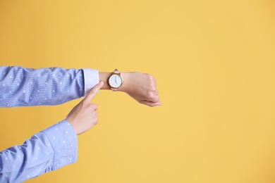 Young woman with wristwatch on color background. Time concept