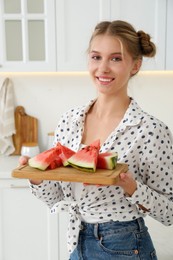 Beautiful teenage girl with slices of watermelon in kitchen