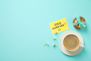 Photo of Delicious coffee, cookies, flowers and card with GOOD MORNING wish on light blue background, flat lay. Space for text