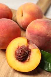 Photo of Cut and whole fresh ripe peaches on wooden board, closeup