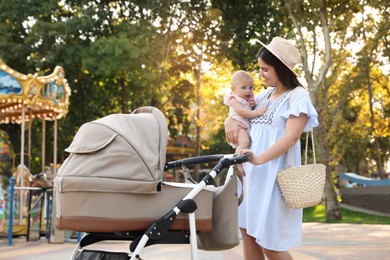 Photo of Happy mother with baby and stroller walking in park