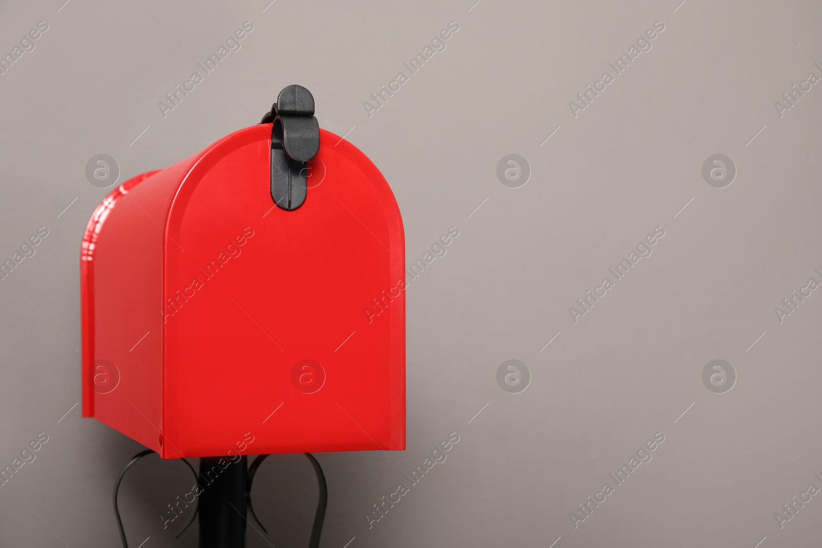 Photo of Closed red letter box against grey background. Space for text