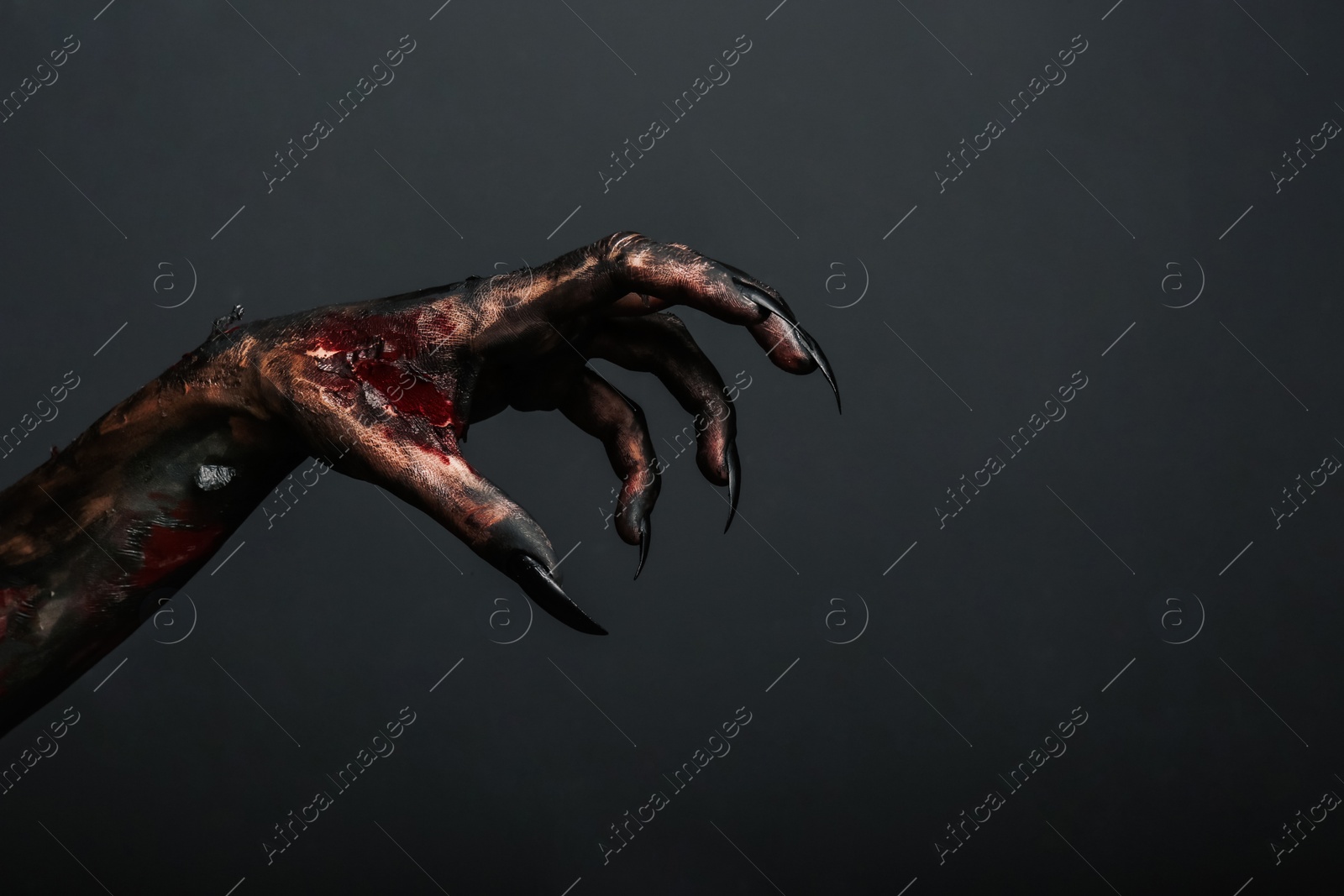 Photo of Scary monster on black background, closeup of hand with space for text. Halloween character