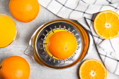 Photo of Fresh ripe oranges, juice and squeezer on grey table, flat lay