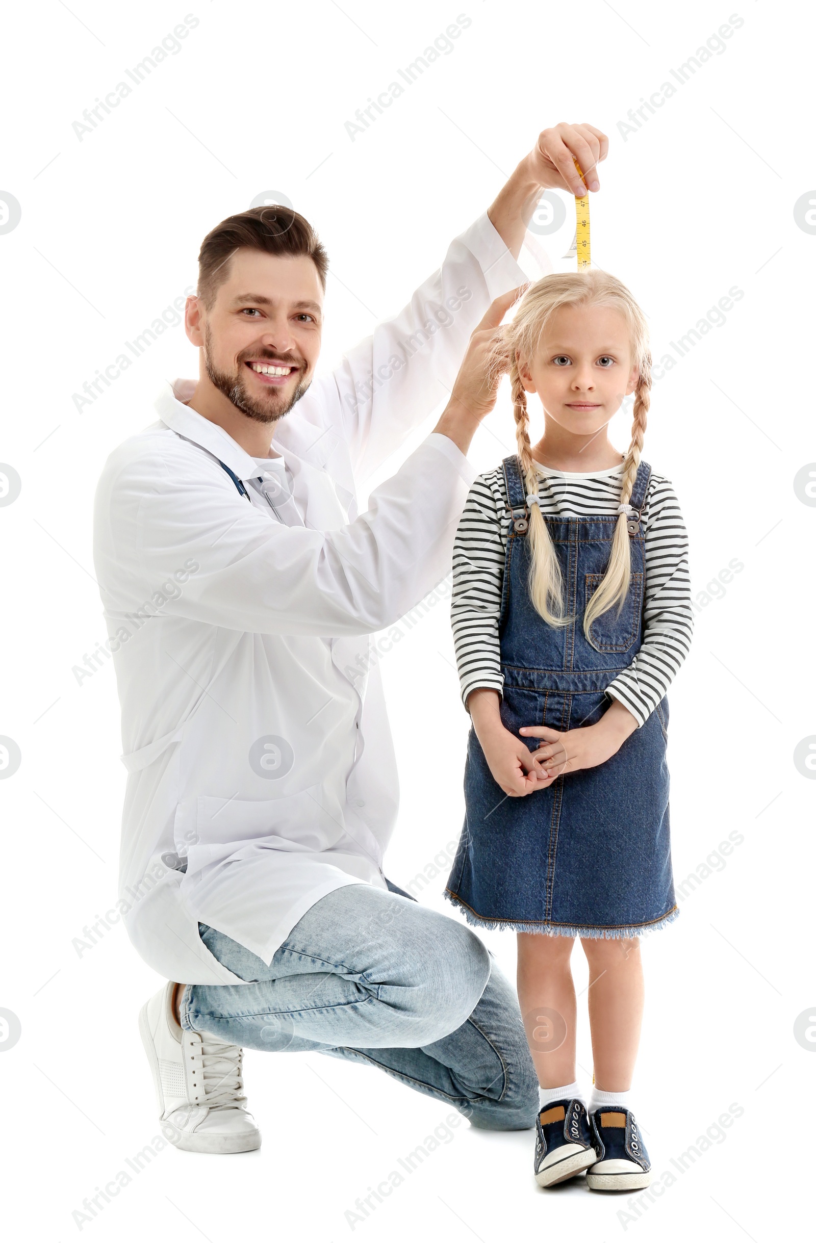 Photo of Doctor measuring little girl's height on white background