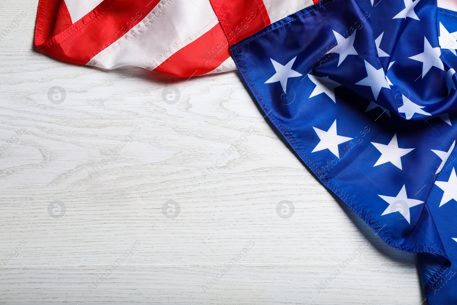 Photo of American flag on white wooden table, top view. Space for text