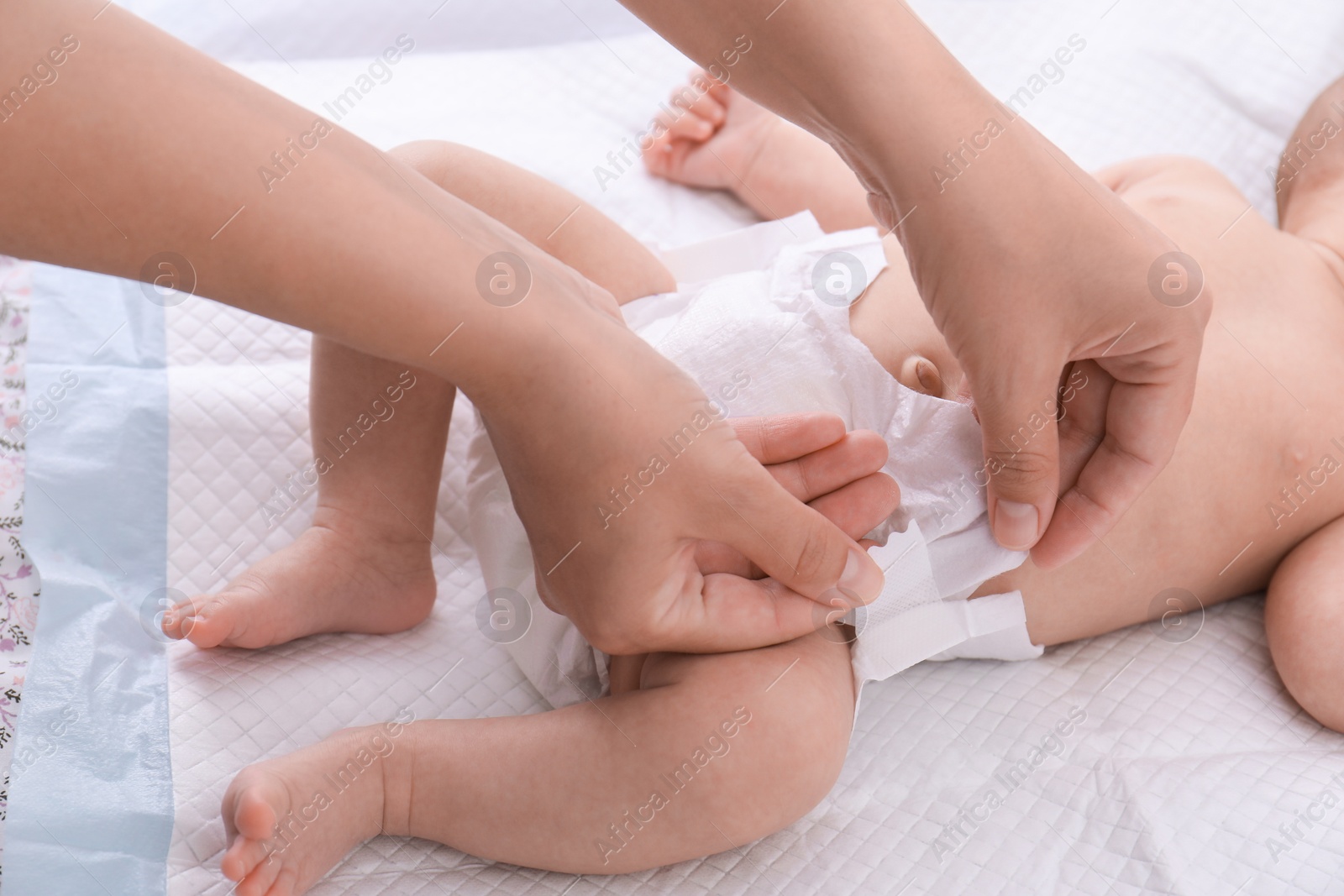 Photo of Mom changing baby's diaper on bed at home, closeup